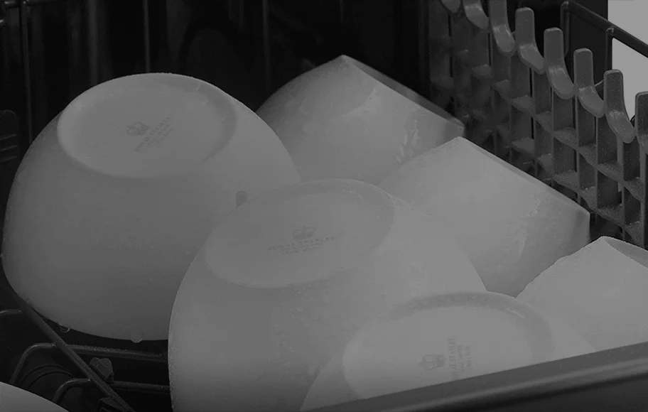 식기세척기 내부에 여러 개의 그릇이 가지런히 놓여 있는 모습입니다. 그릇들은 뒤집혀 있으며, 세척기 내부의 선반과 그릇의 배열이 잘 보입니다. 그릇의 표면에는 작은 로고와 텍스트가 인쇄되어 있지만, 자세한 내용은 식별되지 않습니다. 세척기 내부는 어두운 색조로 이루어져 있으며, 그릇의 밝은 색상과 대조를 이루고 있습니다.